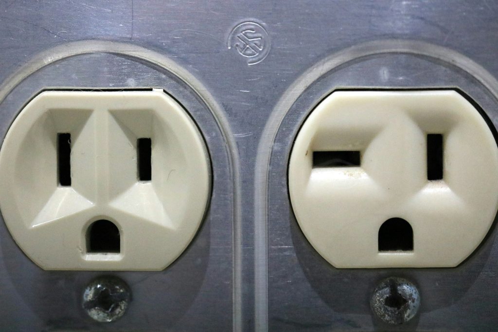 An old household outlet in a wall, its faceplate discoloured