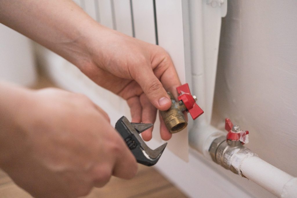 Hands fitting a brass gas valve to a pipe with an adjustable wrench.