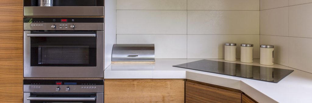 A stainless microwave and oven stacked in a wood run, displays lit red.
