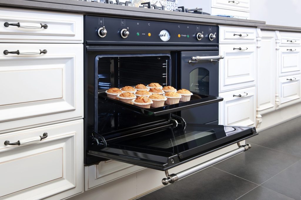 A black built-in oven open with a tray on the rack.