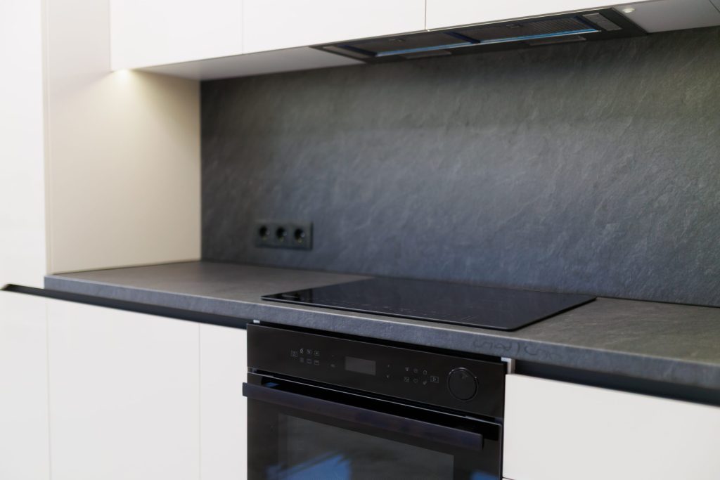 A black glass cooktop set into a slate worktop above a built-in oven.