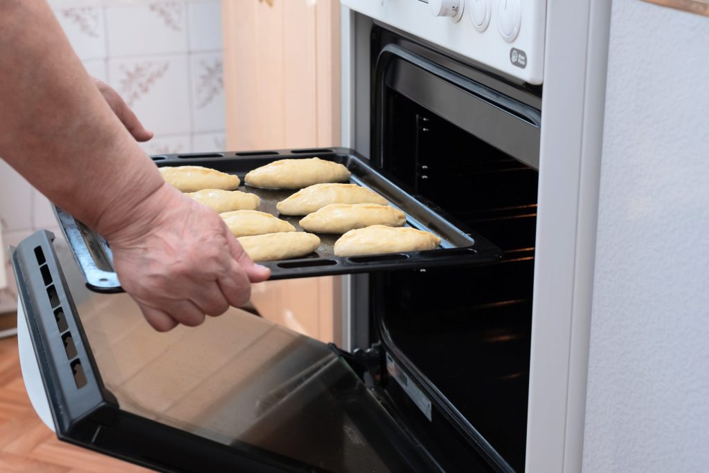 Baking tray of dough placed in oven.