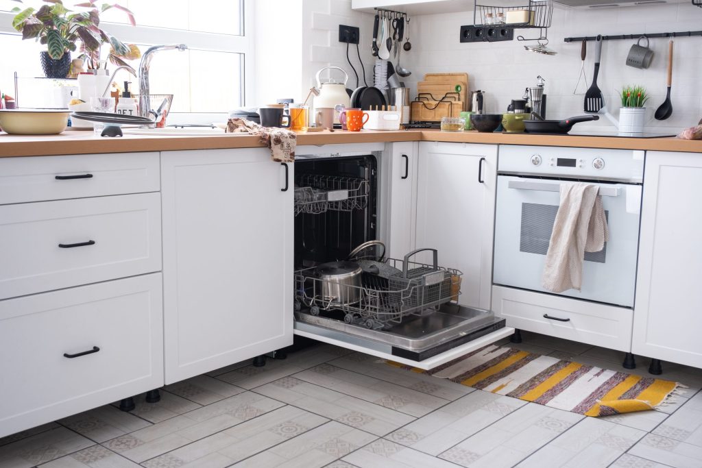 Bright kitchen with dishes and open dishwasher.