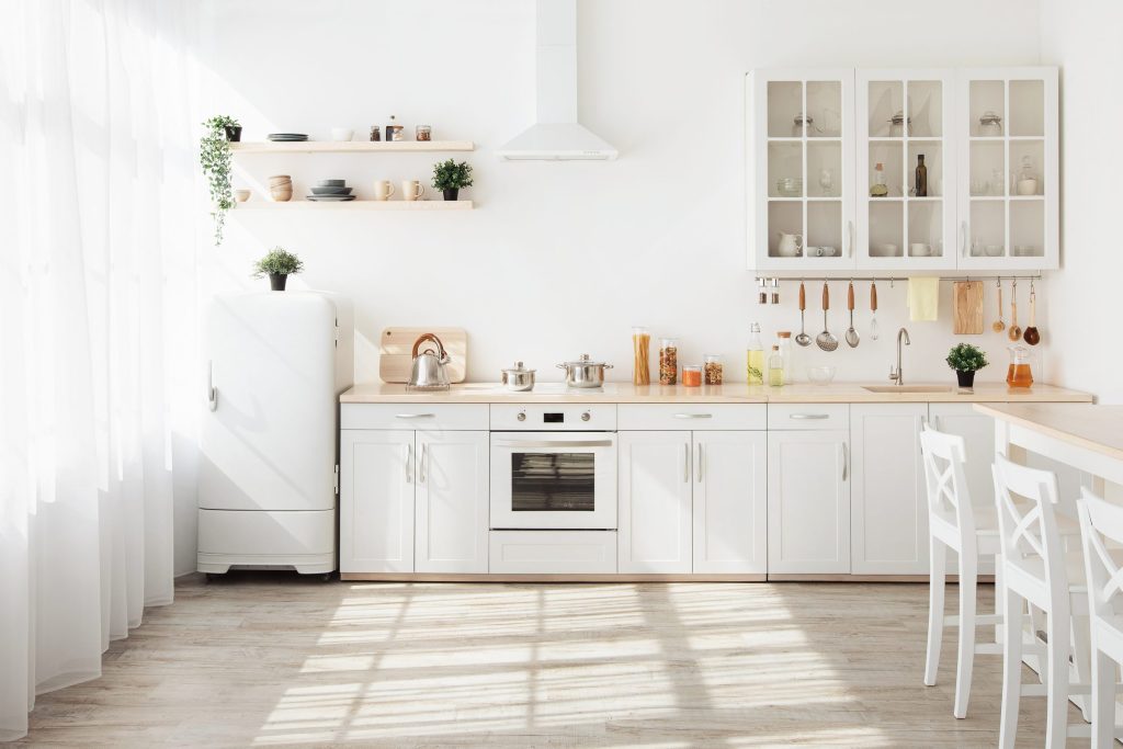 An oven in a bright modern kitchen interior with white decor.
