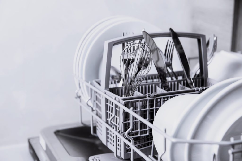 Clean dishes and utensils inside a dishwasher.