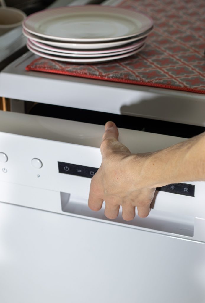 Close up of a female hand opening the dishwasher.