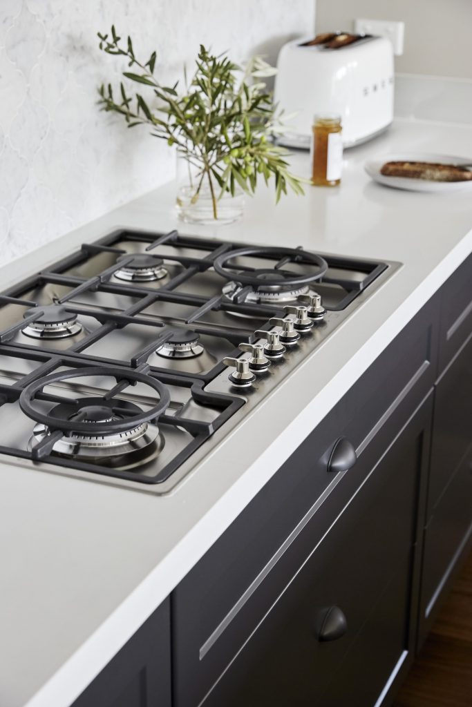 An oven in a elegant kitchen counter with toaster and olive.