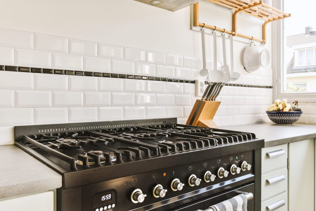 An elegant kitchen with a black range set into pale cabinetry, knives and a chopping board on the counter beside it.