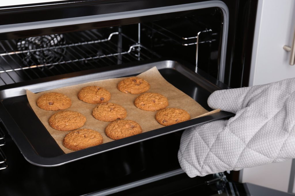 A tray of freshly baked cookies lifted out of the oven of a range.