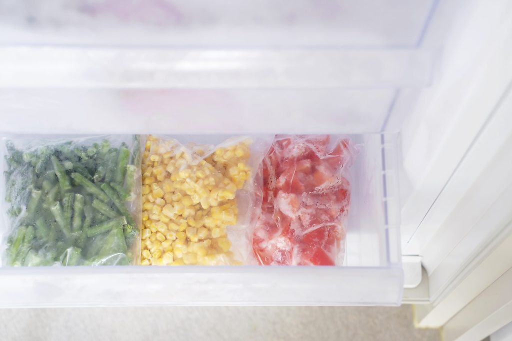 Frozen vegetables in plastic bags in freezer close.