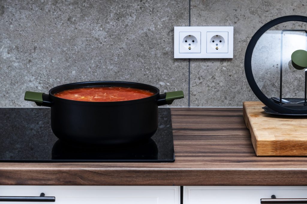 A pan of soup coming to the boil on a cooktop.