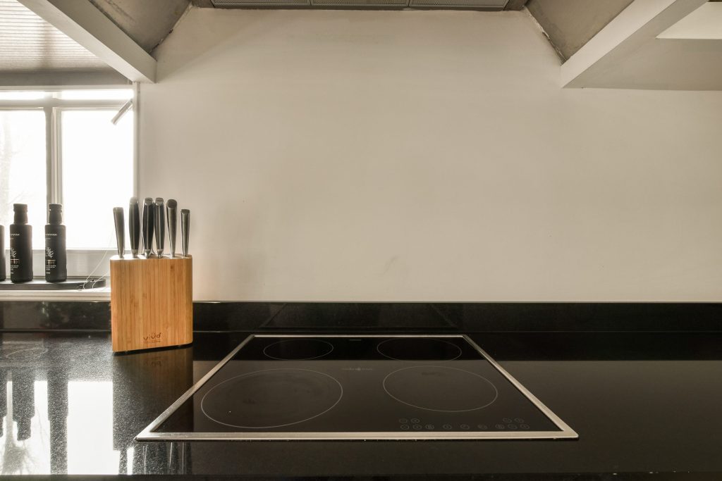 A kitchen countertop beside the range, with a knife block and a bottle of olive oil standing on the stone.