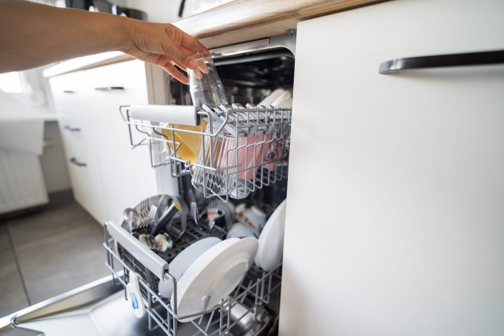 Loading the dishwasher with glasses and plates.