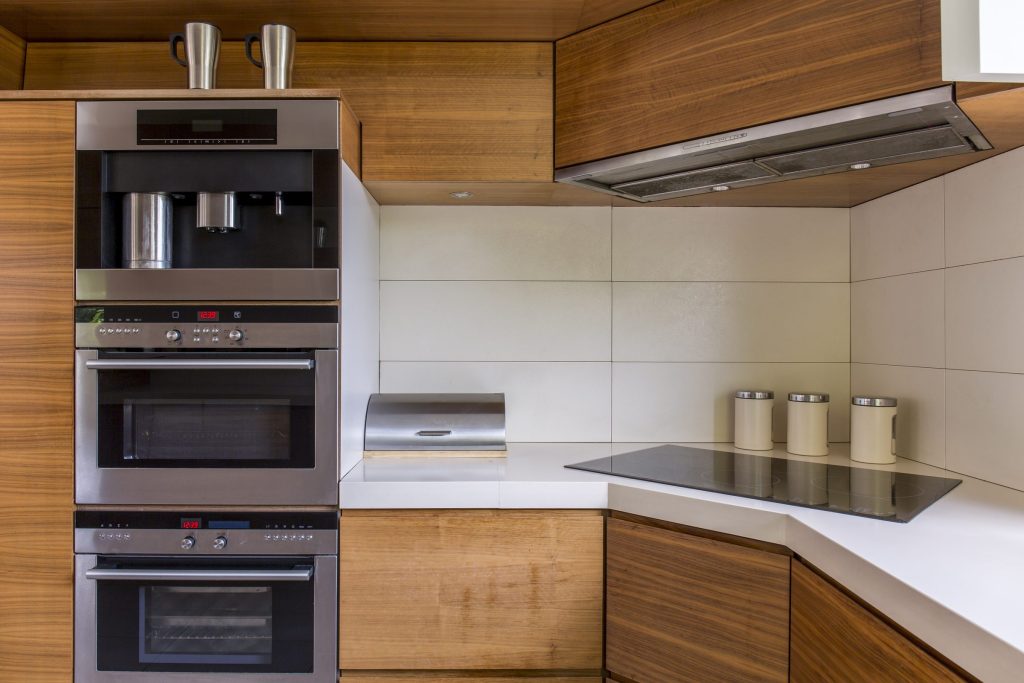 An oven in a modern kitchen interior design with wood cabinets.