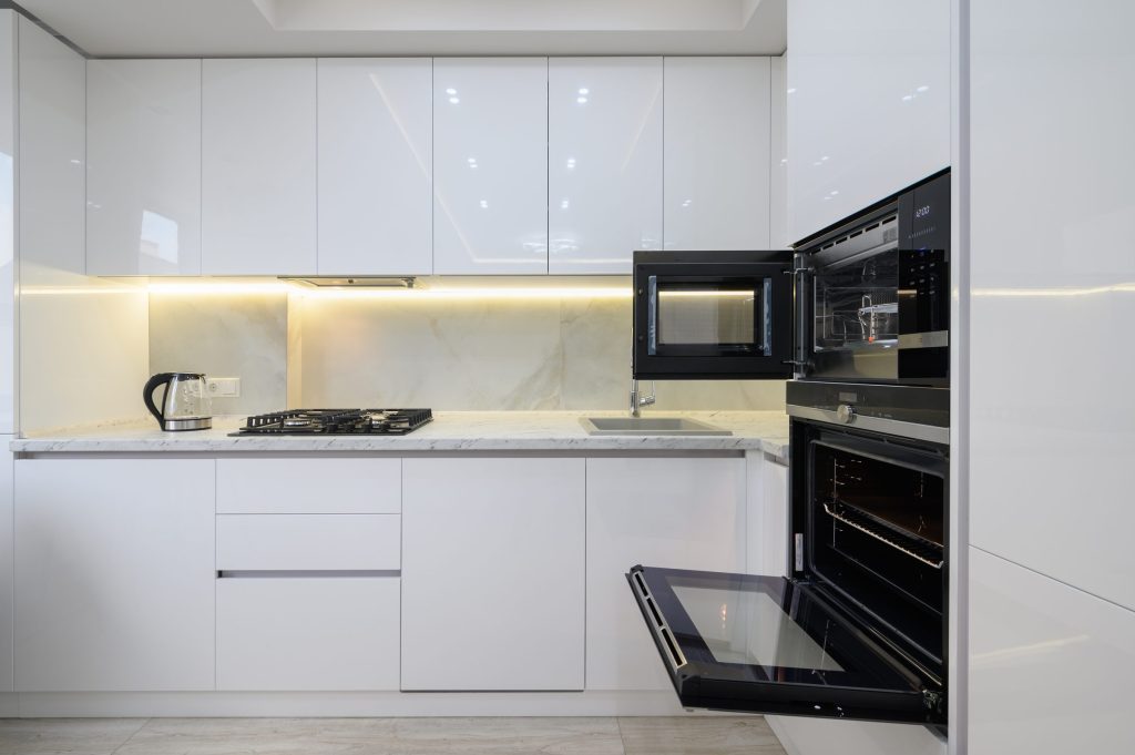 An oven in a modern kitchen interior with white cabinets.