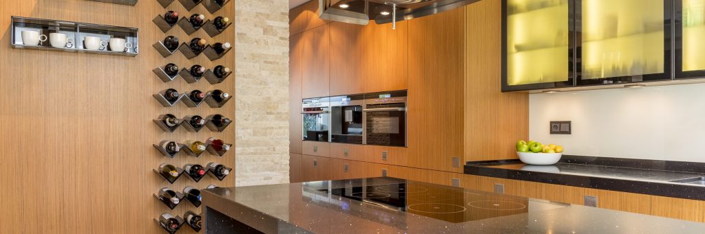An oven in a modern kitchen interior with wine rack and fruit.
