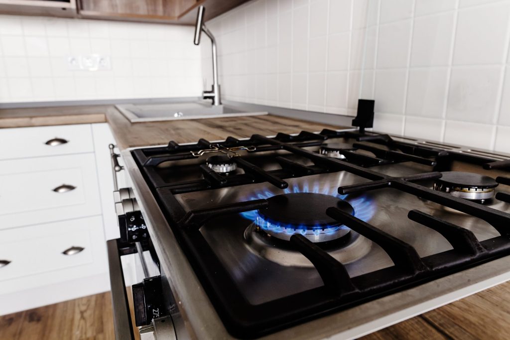 Modern kitchen stove with a blue flame burning.