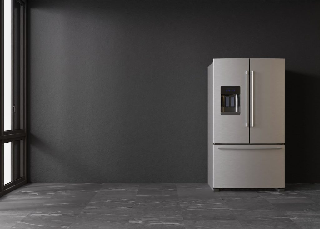 Modern silver refrigerator in room with black wall.