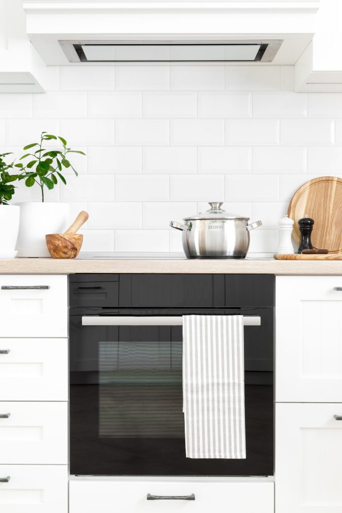 An oven in a neutral kitchen with cookware and wooden accents.