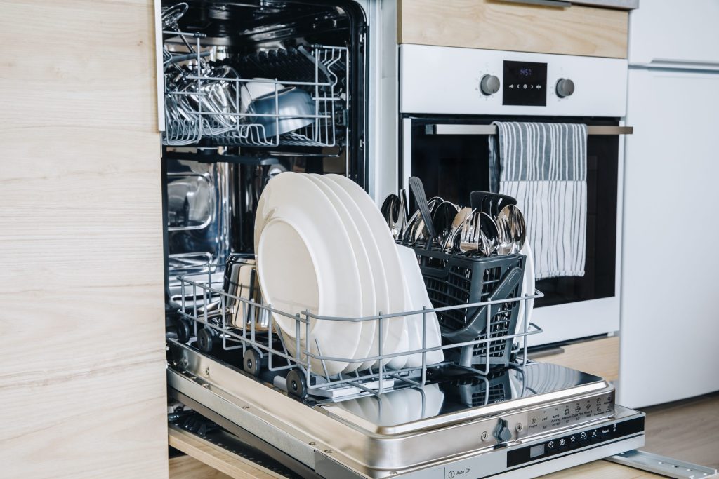 Open dishwasher with clean dishes and silverware.