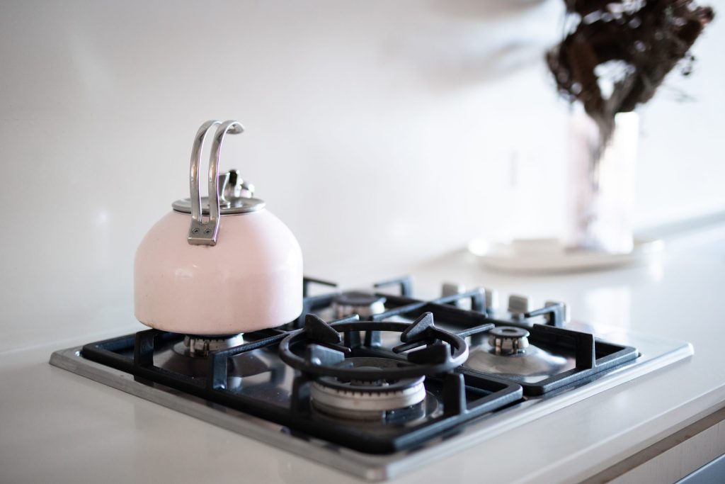 Pale pink tea kettle on a modern stove.