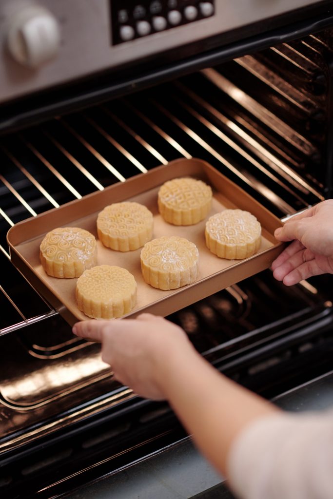Person baking delicious round pastries in oven.