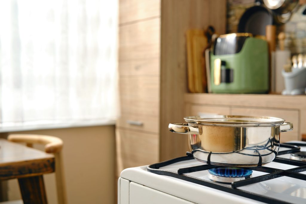Shiny stainless steel pot boiling on a gas stove.