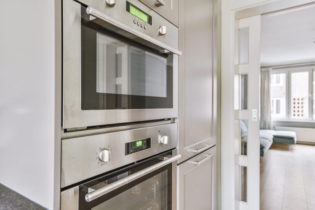 A stacked oven and combination oven built one above the other in a tall run of kitchen cabinets.