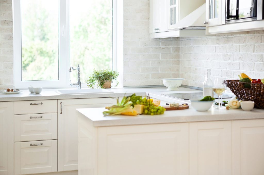 An oven in a well lit kitchen with fresh food on the counter.