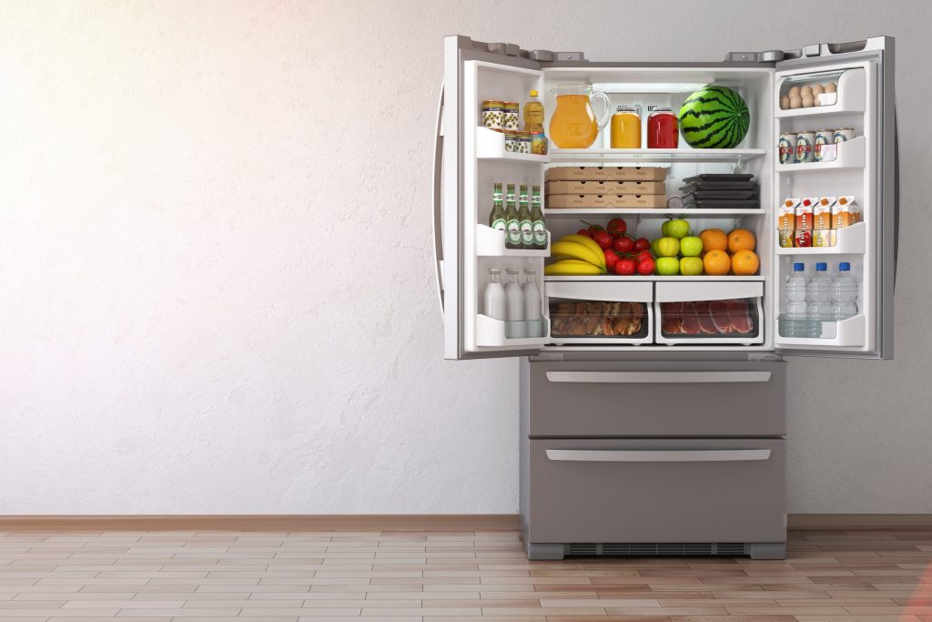 A French-door refrigerator standing open on a stocked interior with two freezer drawers below it.
