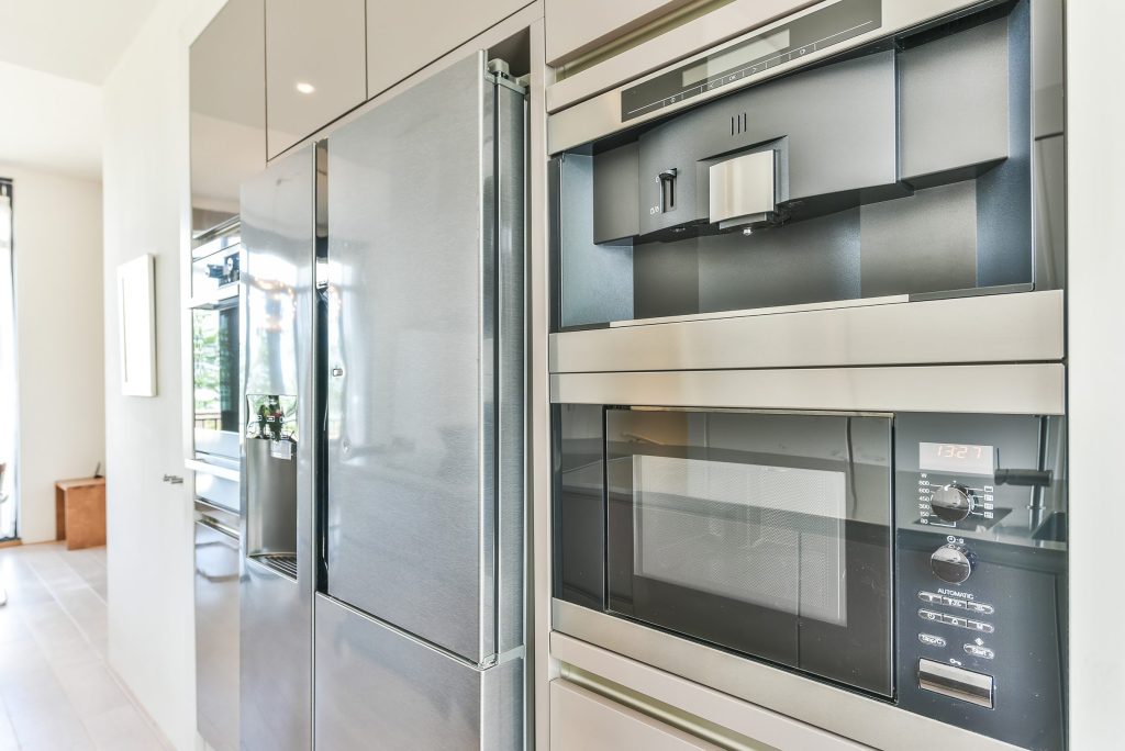 A built-in microwave and a coffee system in a tall stainless housing beside a fitted refrigerator column
