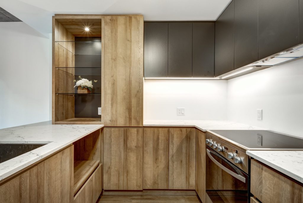 An oak galley kitchen with a flush cooktop and an oven under the counter.