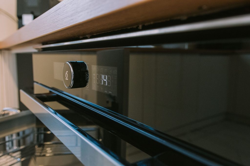 The fascia of a built-in oven, dial and display lit.