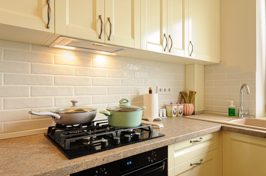 Two pans on a black hob in a stone counter.