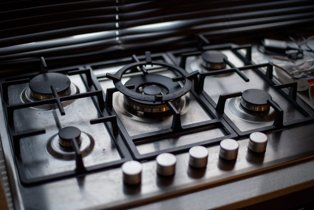 A five-burner gas deck seen along the cast grates, control knobs at the front edge.