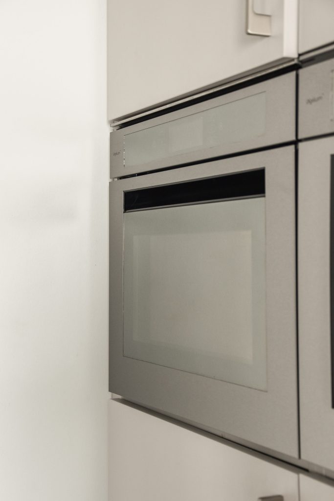 A slim built-in oven in a white cabinet run. Front zoomed at 3x: cabinet joints, no lettering.