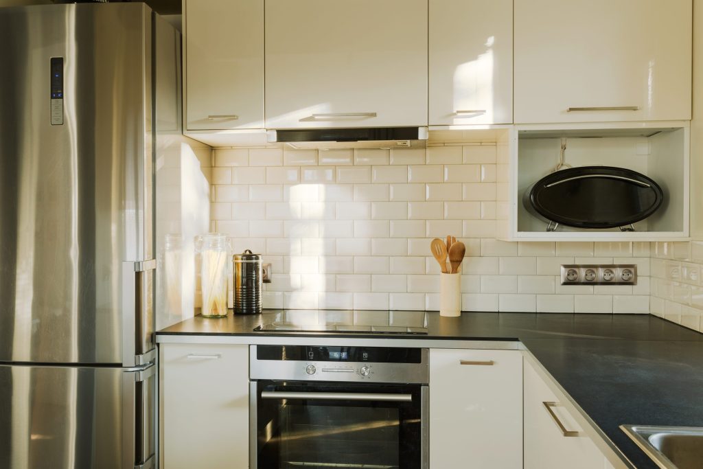 A galley kitchen with a built-in oven in a run of steel appliances.