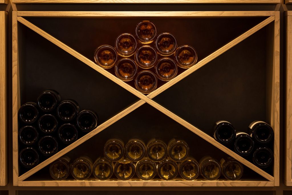 Bottles stacked in a wooden X-frame rack.