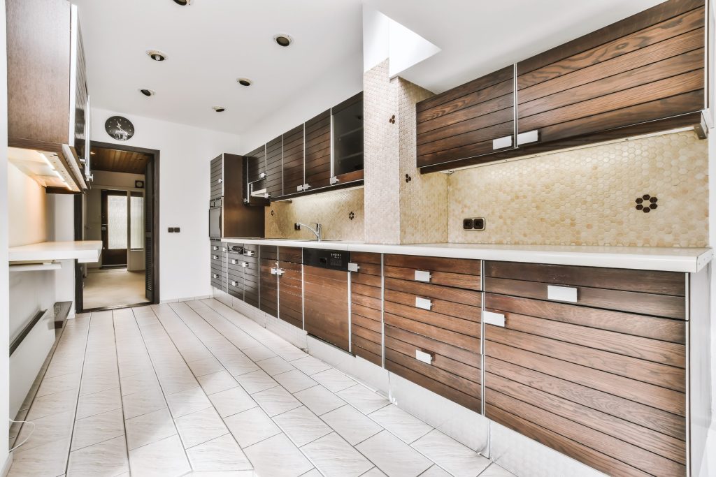 A narrow galley kitchen in dark stained wood with a honeycomb tile splashback and a black oven in the run.