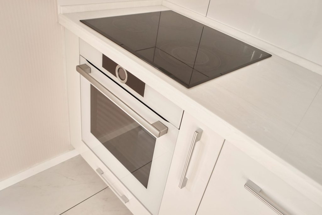 A black ceramic hob in a white counter above a built-in oven.