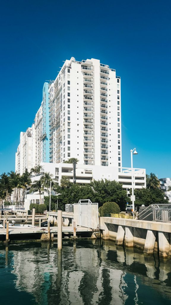 A white residential tower above a marina and its docks